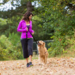 A woman and her dog taking a walk in the park